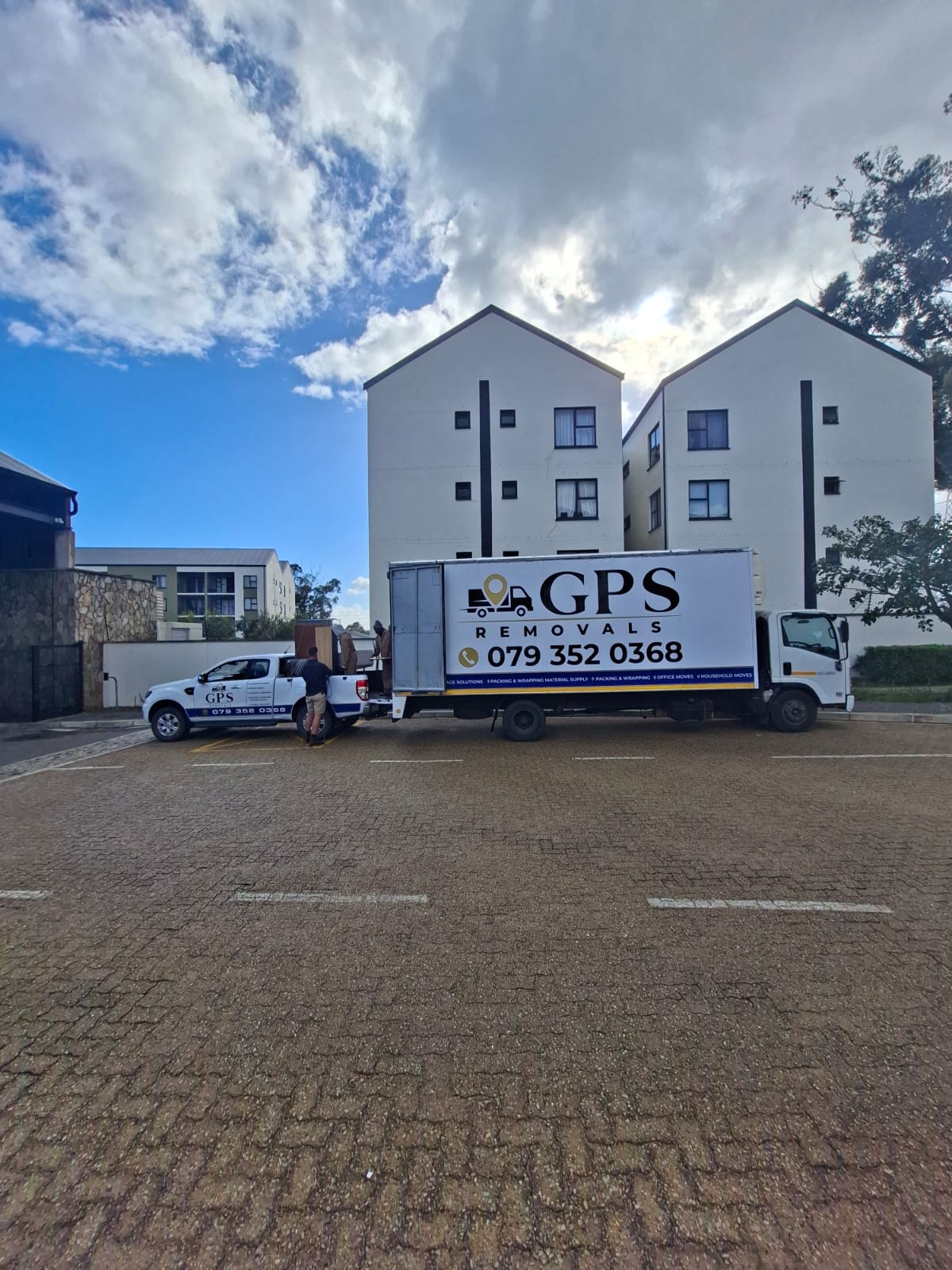 GPS Removals truck and bakkie parked outside an apartment block