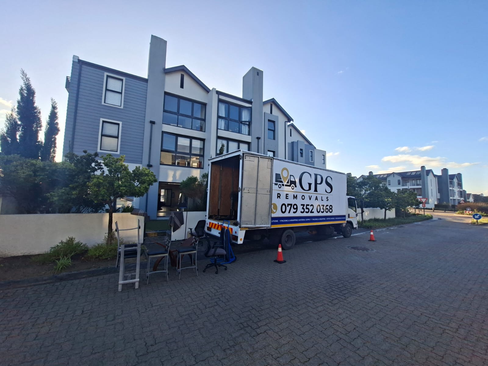 Open GPS Removals truck with furniture on the kerb and safety cones out